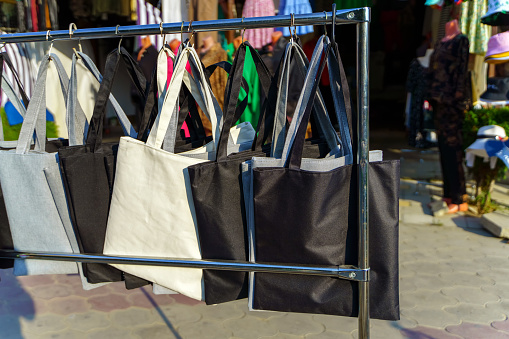 A range of square bags of different colors hang on the rack for sale