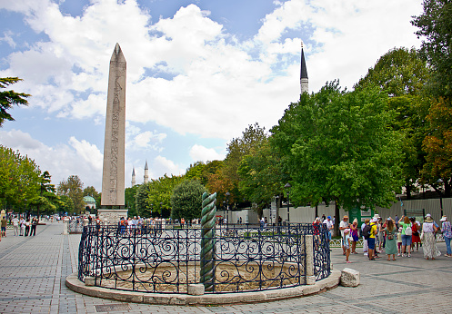 Istanbul,Turkey - August 10, 2022: Tourists near Obelisk of Theodosius, Egyptian obelisk of Pharaoh Thutmose III re-erected in Hippodrome of Constantinople by Roman emperor Theodosius I in the 4th century. And there is also Serpentine column in the Hippodrome of Constantinople, Sultanahmet