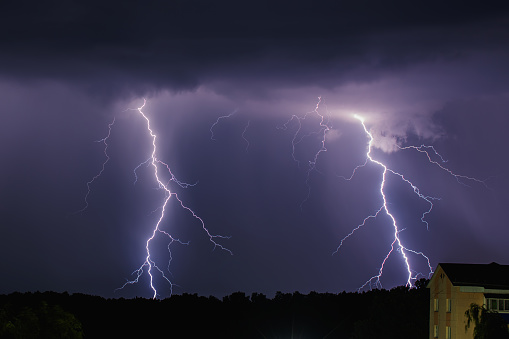 Lightning on background of night sky. Weather and climate. Flash of lightning. Natural disaster. Dark dramatic sky. Storm