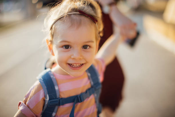 glückliche tochter, die von ihrer unkenntlichen mutter zur schule gebracht wird - family walking child toddler stock-fotos und bilder