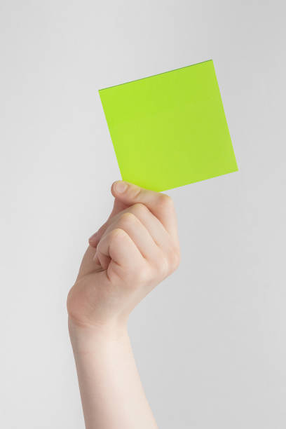 istock child hand holding a square green blank reminder or paper notes above a white and gray background, copy space 1416625600