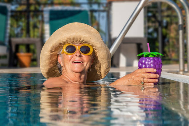 수영장 옆에서 웃고있는 성숙한 여성을 입은 모자와 선글라스 - swimming pool sensuality women sex symbol 뉴스 사진 이미지