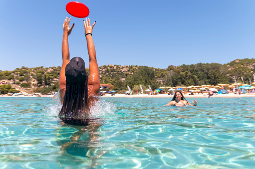 Happy young couple playing frisbee in the sea. Traveling, vacation and fun