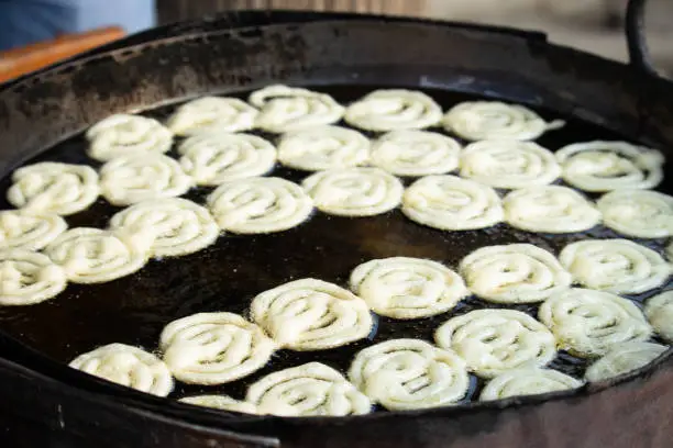 Photo of Fresh Spiral Concentric Cirle Shaped Jalebi Also Known As Jilapi, Jilebi, Jilipi, Zulbia, Jerry, Zalebi, Mushabak Mithai By Dhaba Halwai Being Deep Fried In Hot Boiling Desi Ghee Oil