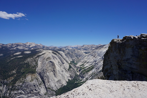 Person overlooking vast mountains of Yosemite National Park from Half Dome