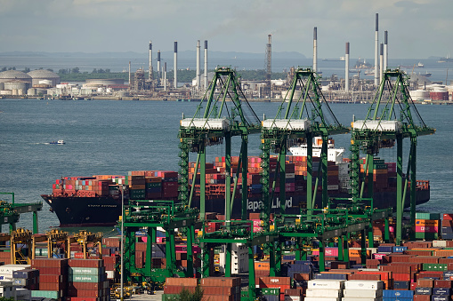 Singapore container port with ship unloading and Jurong Island in the backgrouond