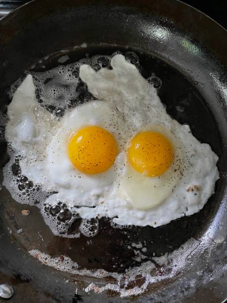 istock Eggs frying in cast iron pan sunny-side up 1416708913