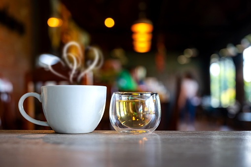 Hot Coffee Cup with tea cup on Wood Table in blurred Coffee Shop background.