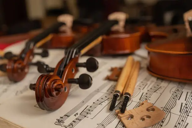 Violins on top of sheet music in a repair shop with different tools