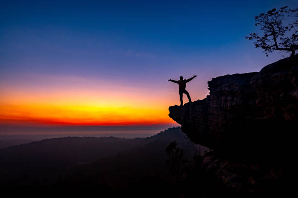 istock Silhouette backpack man standing on top of Mountain at sunset with vivid clouds. 1416721571