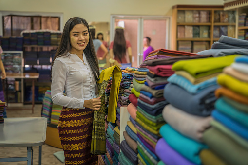 portrait of Myanma woman shopping traditional cloting of Amarapura at local weaving fabric shop in Mandalay Myanmar