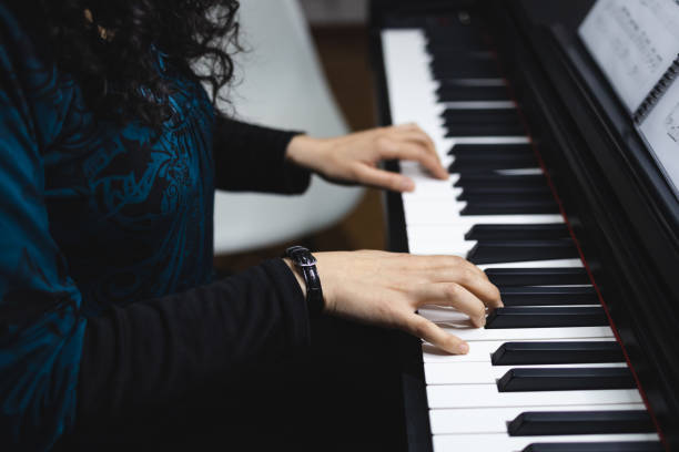 istock Unrecognizable woman's hands playing piano by reading sheet music. Selective focus 1416731001