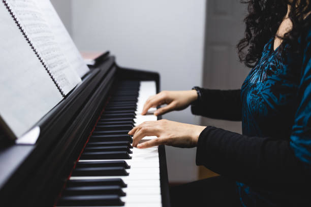 istock Unrecognizable woman's hands playing piano by reading sheet music. Selective focus 1416731508
