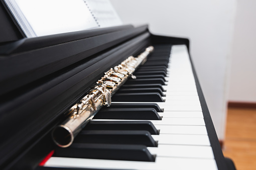 Close up side view of transverse flute on the keys of a piano