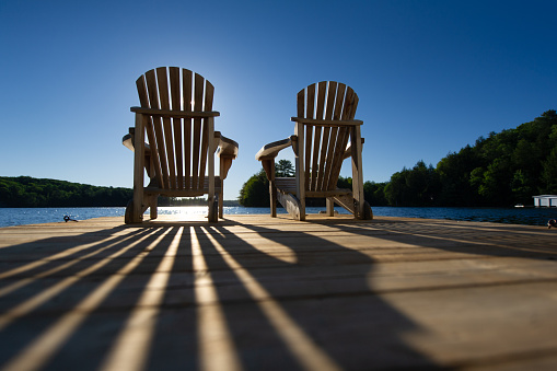 istock Sunrise on two empty Adirondack chairs sitting on a dock 1416741578