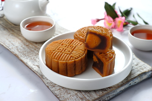 Mooncake, Moon cake-Round shaped Chinese traditional pastry with tea cups on white background, Mid-Autumn Festival concept, close up.