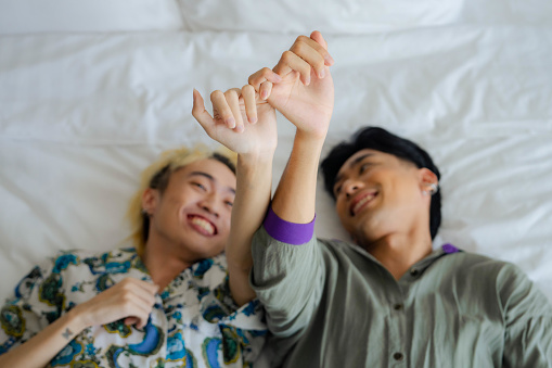 Asian Gay couples happily tease each other in bed on weekend trips.
