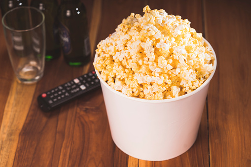 Popcorn in white paper bucket on wooden table background, Popcorn on white cardboard.