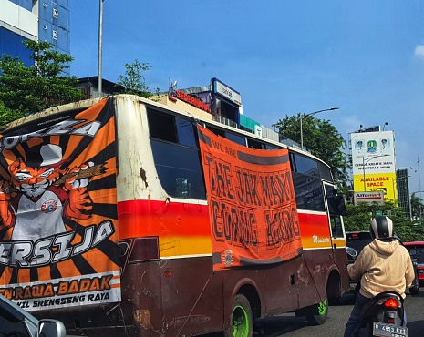 Jakarta in July 2022. Jakarta soccer supporters are mobilizing themselves to the stadium by using an orange bus and orange shirt to watch a match in a stadium.