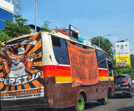 Jakarta in July 2022. Jakarta soccer supporters are mobilizing themselves to the stadium by using an orange bus and orange shirt to watch a match in a stadium.