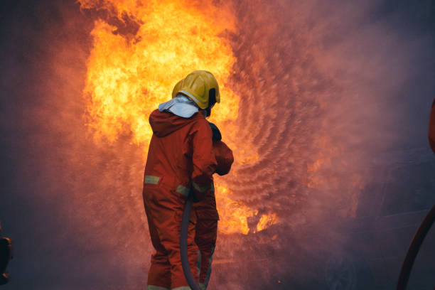 istock Firefighter Rescue training in fire fighting extinguisher. Firefighter fighting with flame using fire hose chemical water foam spray engine. Fireman wear hard hat, safety suit uniform for protection 1416790860