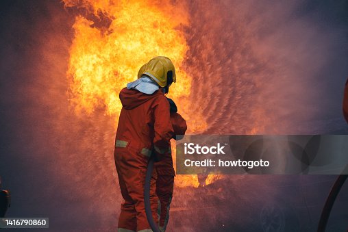 istock Firefighter Rescue training in fire fighting extinguisher. Firefighter fighting with flame using fire hose chemical water foam spray engine. Fireman wear hard hat, safety suit uniform for protection 1416790860