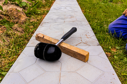 a tool for laying a garden path with stone tiles lies on the finished path. out-of-town landscaping works.