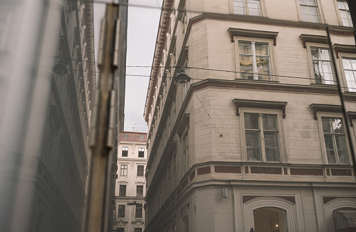View of old and renovated facades of a street in Vienna, 1st district. The opposite houses are reflected in a modern shop window.