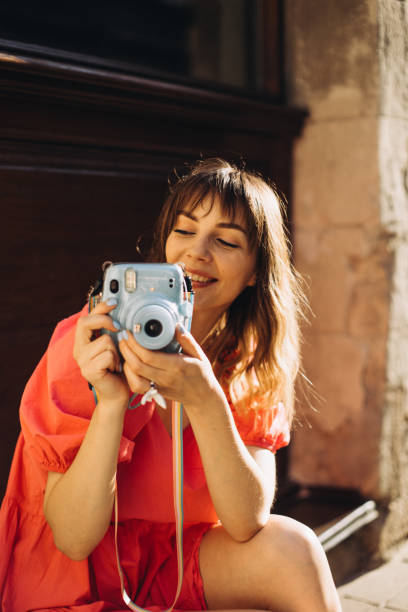 A cheerful cute woman using Instax to take a photo