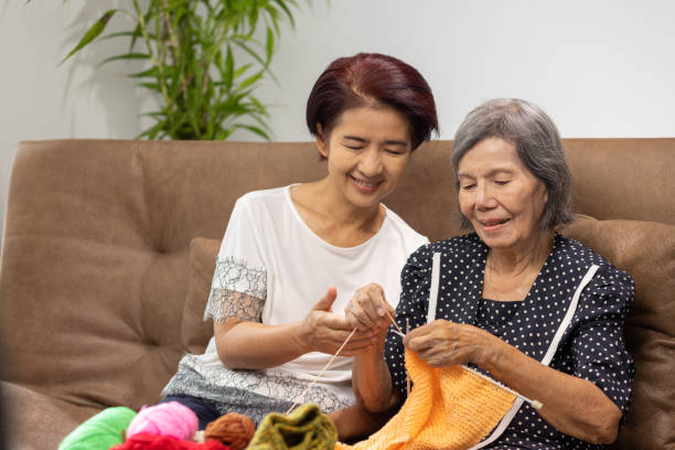 пожилые женщина и дочь вяжут вместе для защиты деменции и потери памяти. - grandmother knitting senior women senior adult стоковые фото и изображения
