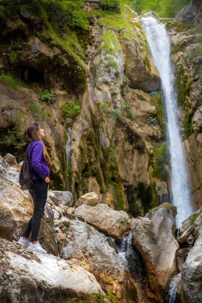 istock Woman in violet jacket looking at a waterfall. 1416811890