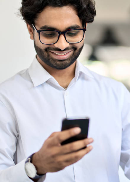 istock Happy young indian business man using smartphone at work in office. Vertical 1416817904