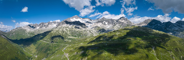 Wide panorama landscape of Dolomites mountains, Alpi Dolomiti beautiful scenic landscape in summer. Italian Alps mountain summits and rocky peaks above green valley alpine panoramic scene