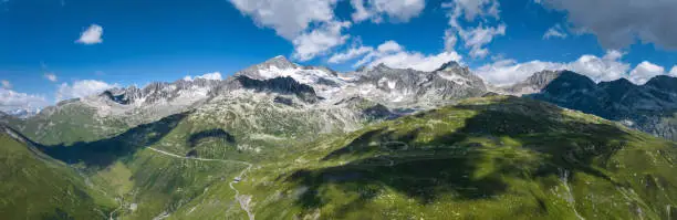 Rhone Glacier View in Summer with famous Furka Pass, a mountain pass - serpentine road in the Swiss Alps connecting the villages and towns of Gletsch & Valais with Realp and Uri. The famous Furka Pass was used as a location in the James Bond film Goldfinger. Drone Point of view towards Rhone Glacier Mountain Range. Stiched XXXL Panorama. Rhone Glacier Mountain Peaks, Furka Pass, Rhone Valley, Canton Valais, Switzerland, Europe