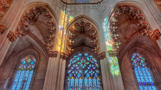 Interior of the Batalha Monastery with rainbow reflections of the stained glass windows on the columns and walls