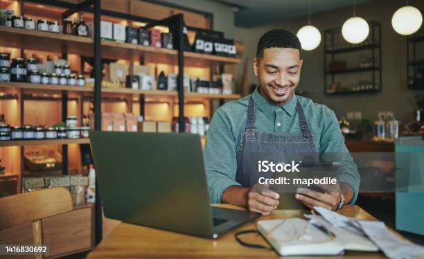 Smiling Deli Manager Working On A Tablet And Laptop In His Shop Stock Photo - Download Image Now