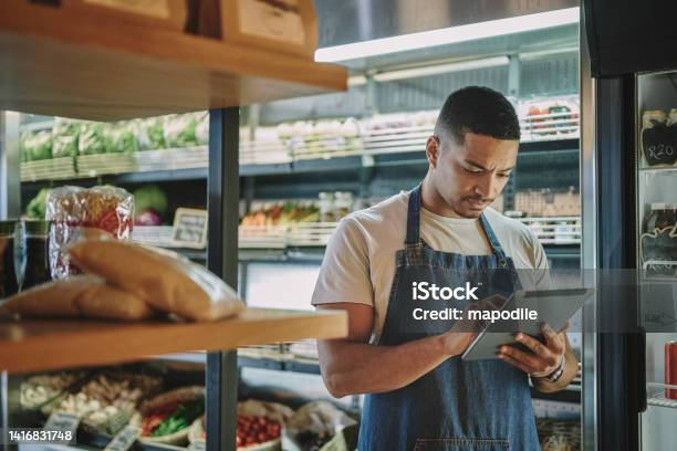 Deli Owner With A Tablet Checking Inventory In His Store Stock Photo - Download Image Now