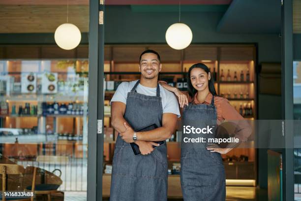 Smiling Young Deli Owners Standing At Their Store Entrance Stock Photo - Download Image Now