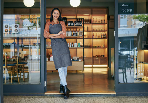 istock Young deli owner smiling while standing at her store entrance 1416833640