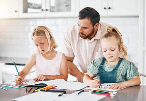 Education, learning and homework with a little girl, her sister and her dad drawing, writing or coloring in the kitchen at home. Single father helping, assist and teaching his daughters about school
