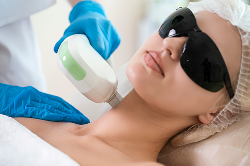 Cosmetology Concepts. Close-up of Young Winsome Woman in UV Protective Glasses During Laser Skin care on Face Using  Rejuvenation Intense Pulsed Light Therapy IPL. Horizontal Composition