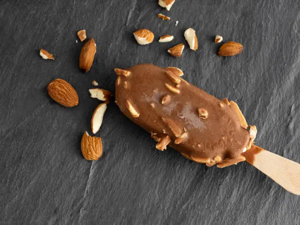 Photo of Stick ice cream, Chocolate ice cream, Chocolate almonds Ice cream bar, Ice cream covered with chocolate and almonds on black background