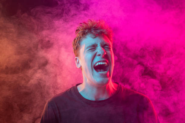 istock Shouting excited young man with bright emotions isolated over pink background with smoke. Concept of mental health, art, human emotions 1416860671