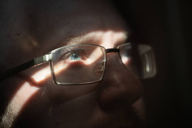 A man's portrait in close-up. He thoughtfully looks up,  illuminated by a small sunbeam