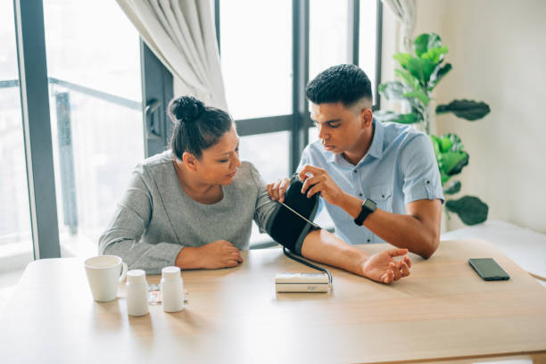 Son measuring blood pressure of mother stock photo