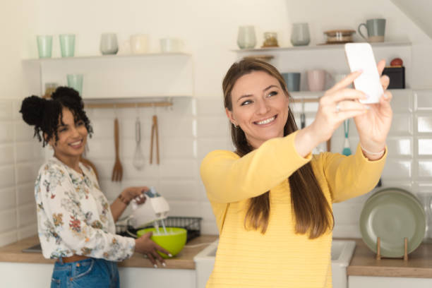 istock Two happy friends taking a selfie while making a cake 1416884106
