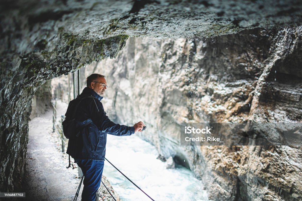 Attractive man sightseeing gorge and taking photos in Bavaria Stream - Body of Water Stock Photo