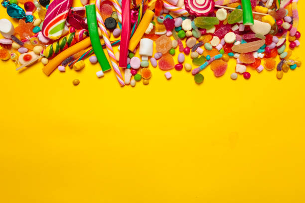 caramelos de colores sobre fondo amarillo - bombones fotografías e imágenes de stock