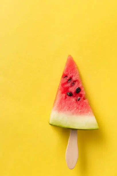 Photo of Fresh and ripe berry. Summer watermelon slice popsicles on bright yellow background. Design for cover, wallpaper, device screen