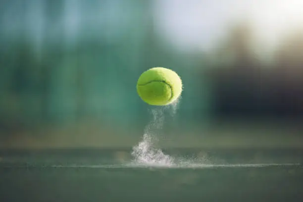 Closeup view of a tennis ball bouncing on a court in a sports club during the day. Playing tennis is exercise, promotes health, wellness and fitness.